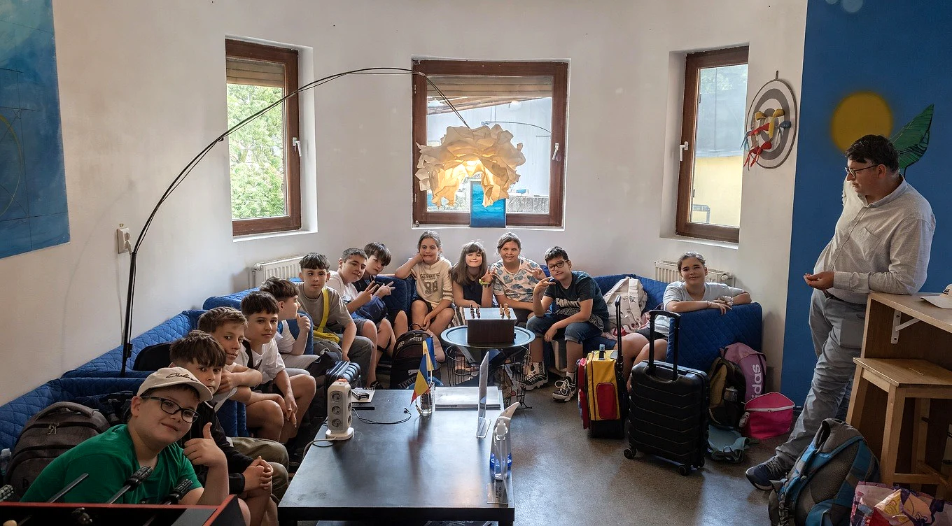 Grup școlar în lounge-ul Popcorn Hostel din București, cu bagaje și jocuri în spațiul comun