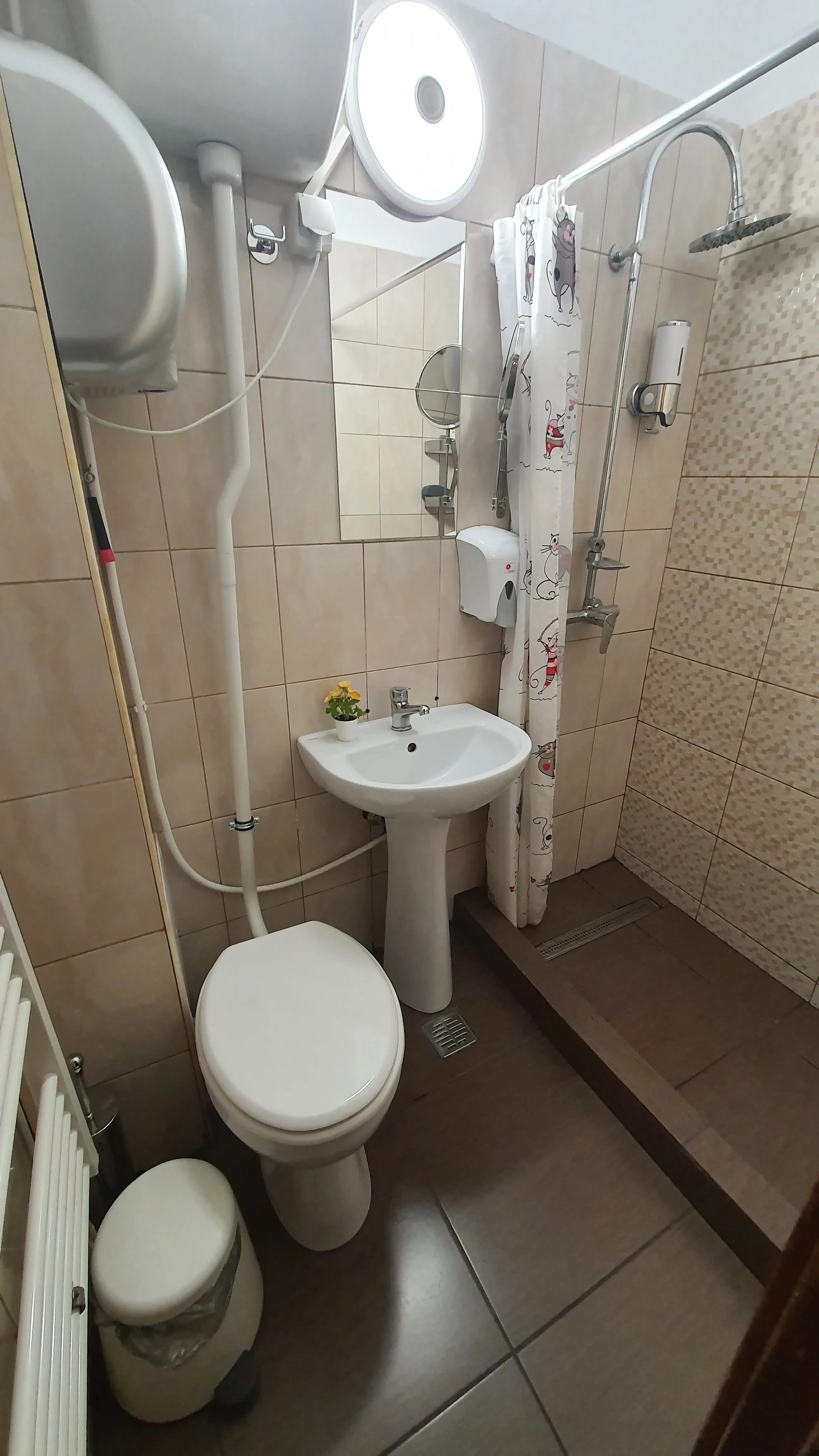 Petite salle de bain partagée au Popcorn Hostel : douche à rideau, lavabo, toilette et radiateur.