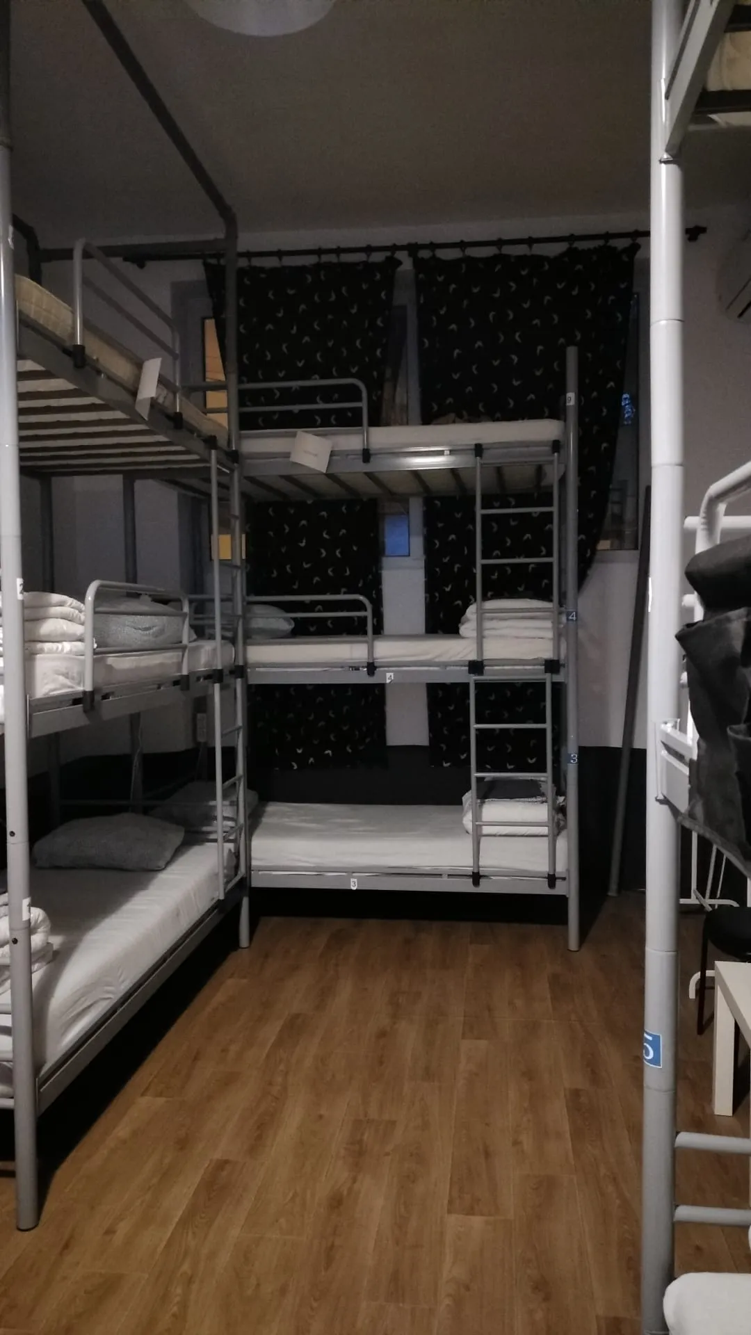 Popcorn Hostel ඇඳන් 9ක පොදු ඩෝමය — මහල් 3ක bunk ඇඳන්, blackout තිර සහ ඕක් parquet බිම.