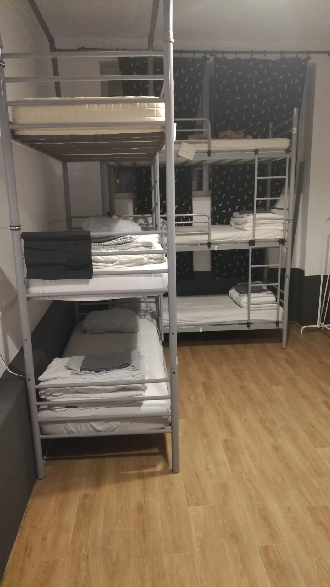 Popcorn Hostel හි සුදු ගෝලීය එල්ලෙන විදුලි පහනක් යට ඇඳන් 9ක පොදු ඩෝමයේ මහල් 3ක bunk ඇඳන් කට්ටලයක්.