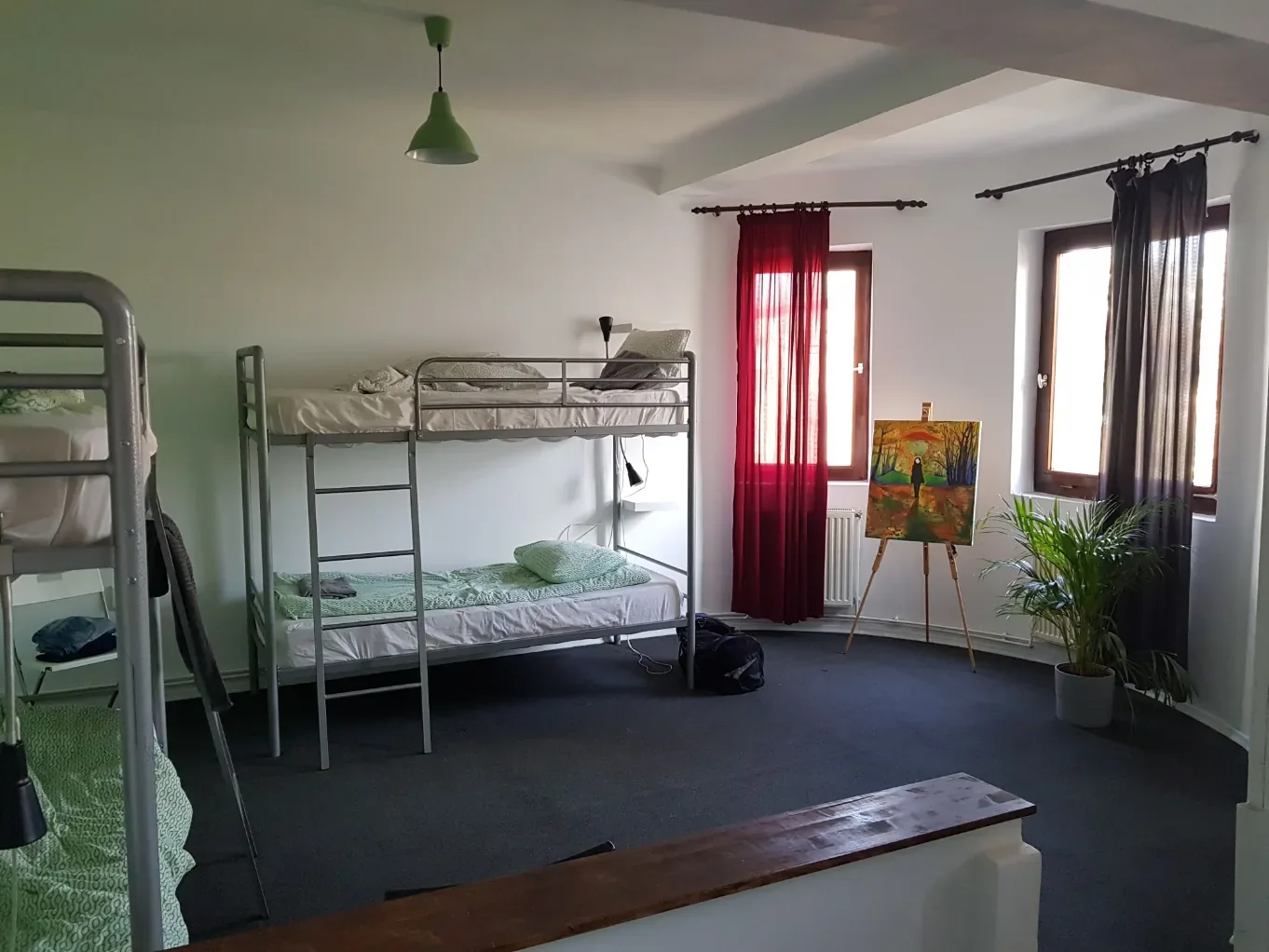 Camerata mista con letti a castello in metallo e un quadro autunnale su cavalletto al Popcorn Hostel Bucarest.