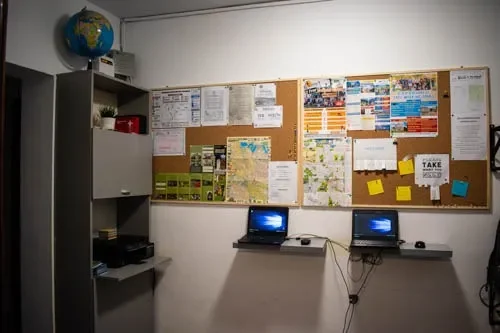 Angolo lavoro per gli ospiti al Popcorn Hostel: laptop, bacheche con mappe della città e guide turistiche di Bucarest.