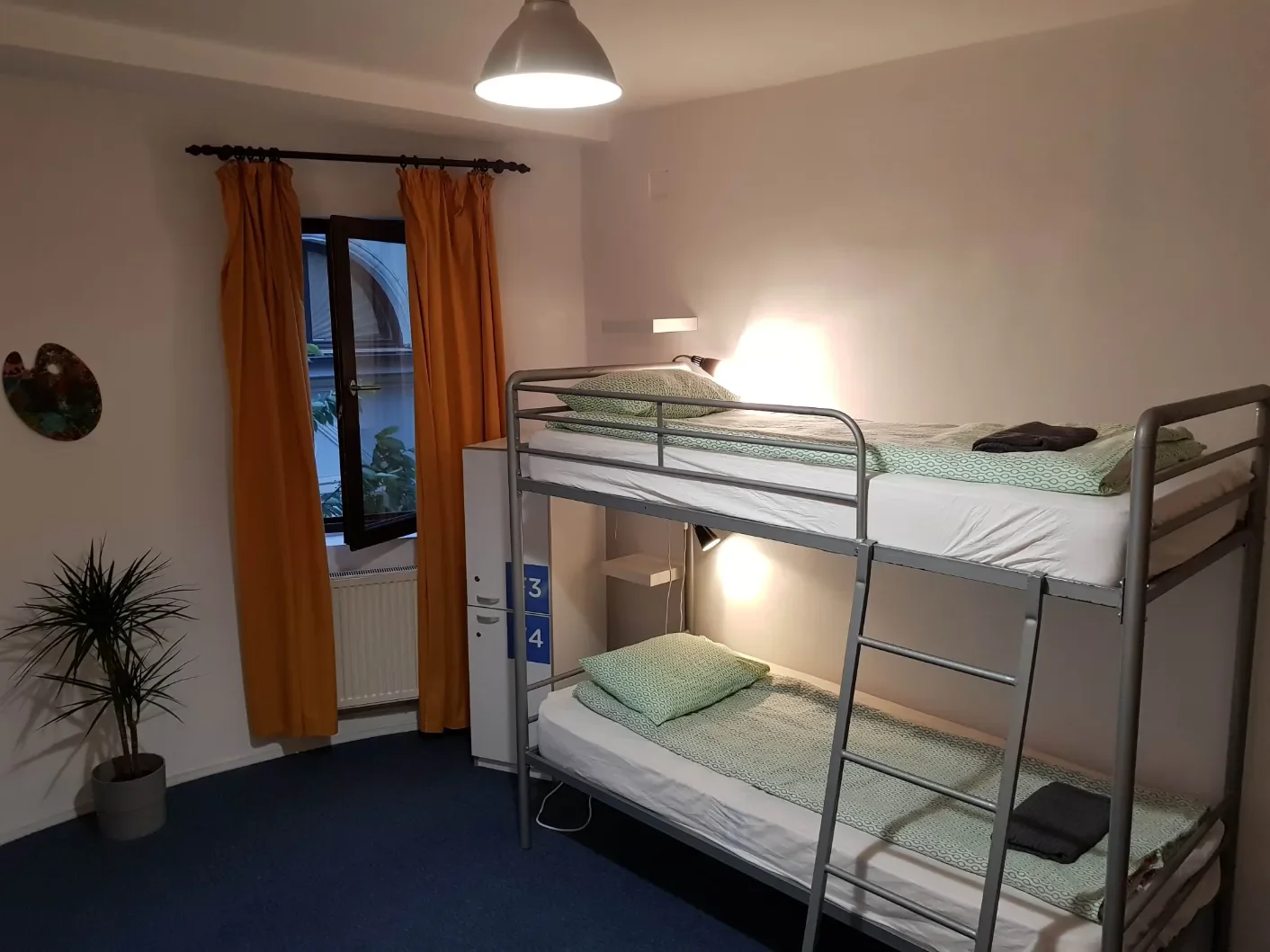 Camerata da 4 con letti a castello in metallo, tende arancioni e armadietti individuali al Popcorn Hostel.