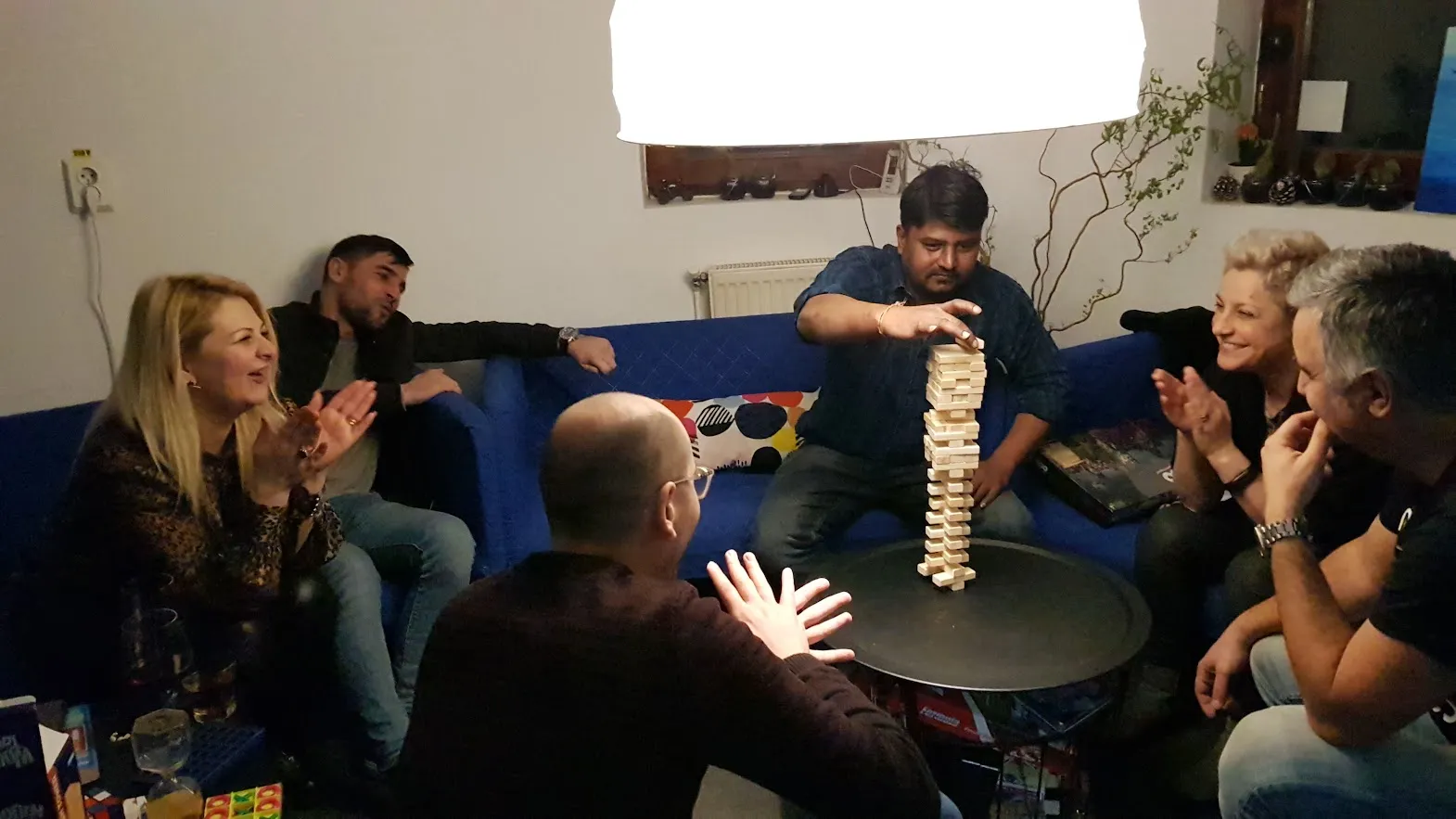 Partie de Jenga géant avec six voyageurs sur les canapés bleus du salon du Popcorn Hostel, en fin de soirée.