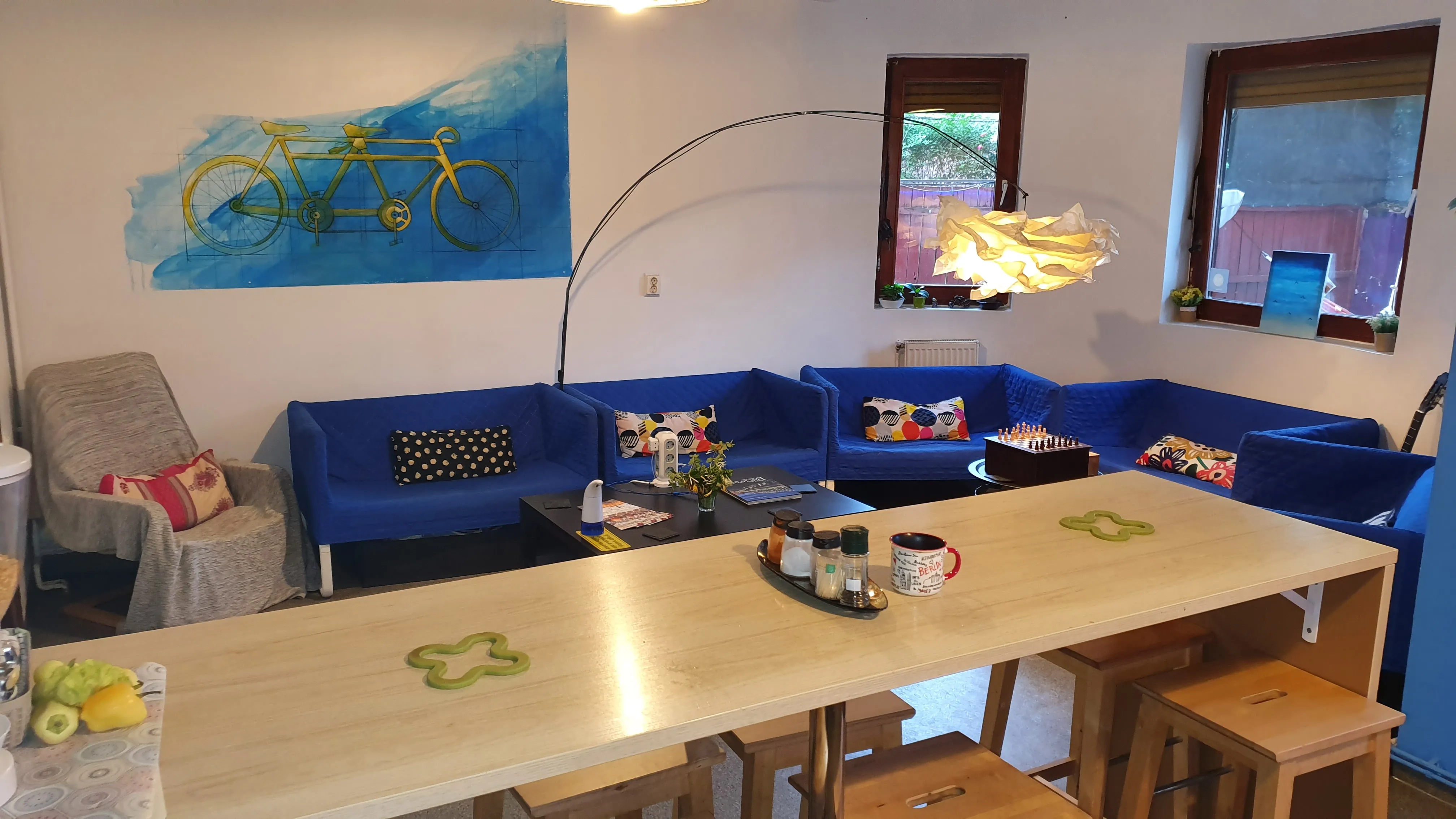 Long bar petit-déjeuner au Popcorn Hostel : tabourets hauts en bois et accès direct aux canapés et à la cuisine.